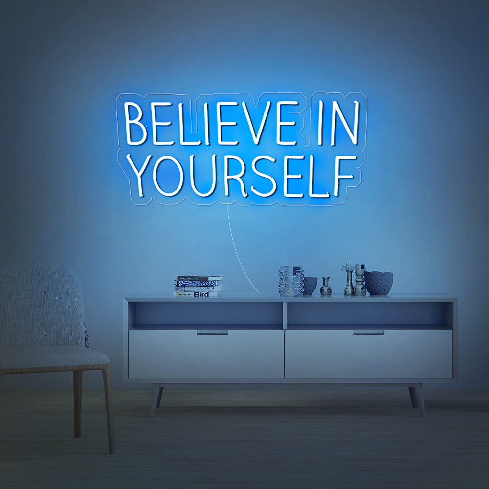 Ijsblauw oplichtend Believe in Yourself sign boven een bureau in een moderne studeerkamer