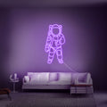 Paars verlichte kosmonaut aan de muur als hippe achtergrond voor streamers en gamers